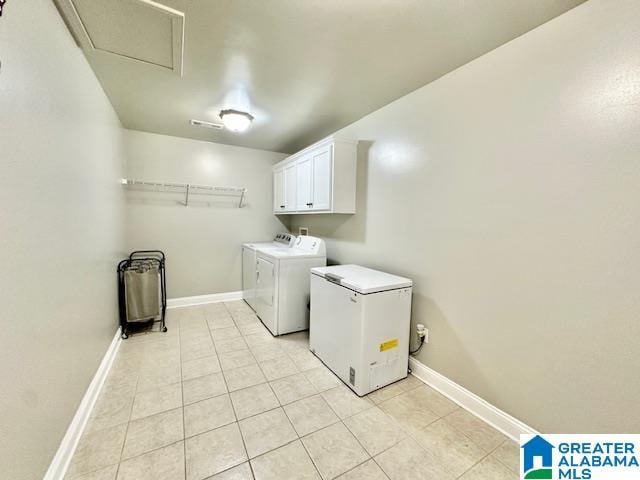 clothes washing area with light tile patterned floors, cabinets, and washer and dryer