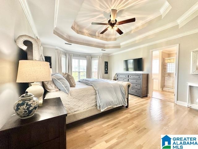 bedroom featuring ornamental molding, light hardwood / wood-style floors, ceiling fan, and a raised ceiling