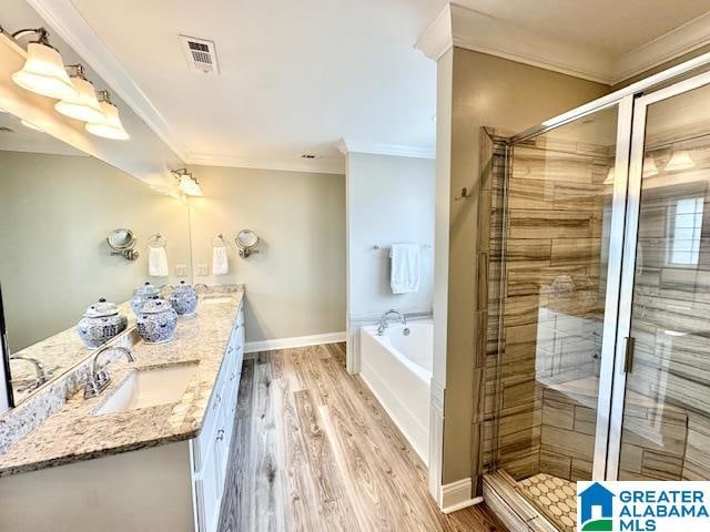 bathroom with crown molding, hardwood / wood-style flooring, vanity, and separate shower and tub