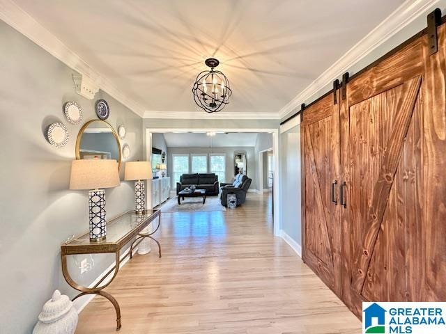 hall featuring light hardwood / wood-style flooring, a notable chandelier, ornamental molding, and a barn door