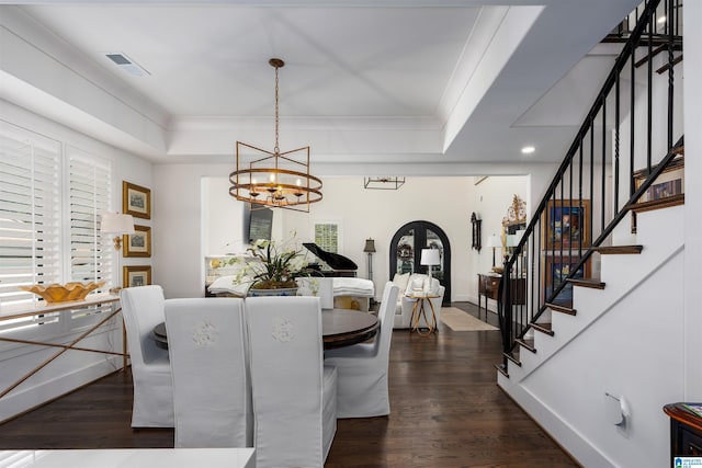 dining area with an inviting chandelier, a raised ceiling, ornamental molding, and dark hardwood / wood-style floors