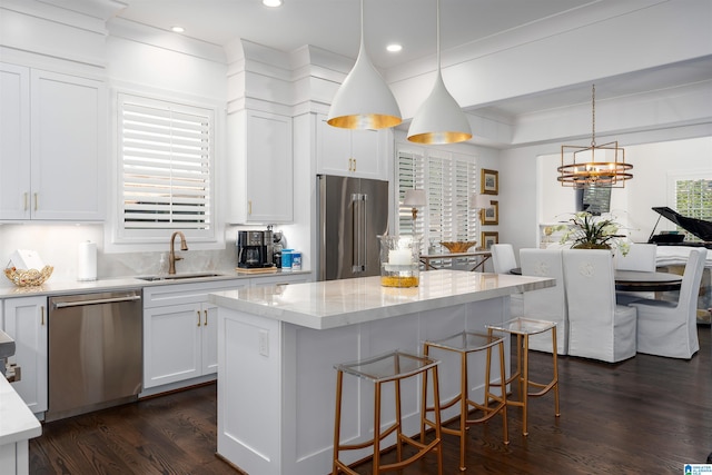 kitchen featuring appliances with stainless steel finishes, a center island, sink, and pendant lighting