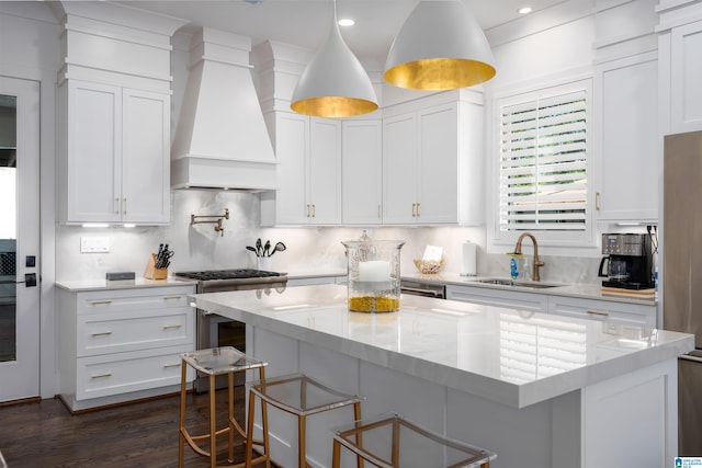 kitchen featuring a kitchen island, premium range hood, light stone countertops, and white cabinetry