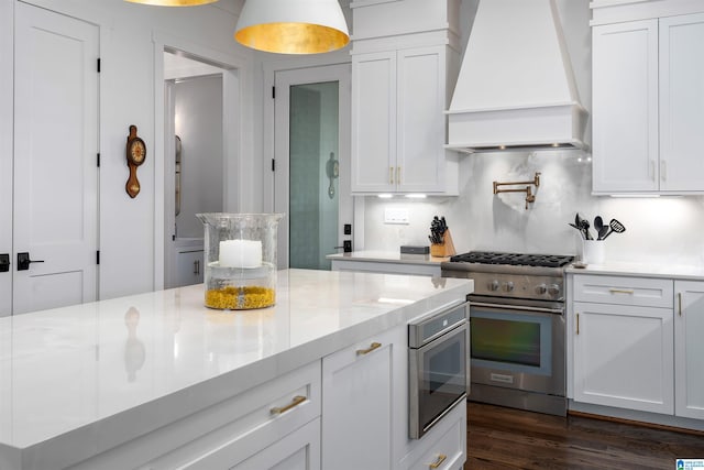 kitchen with light stone counters, white cabinetry, custom exhaust hood, appliances with stainless steel finishes, and dark hardwood / wood-style flooring