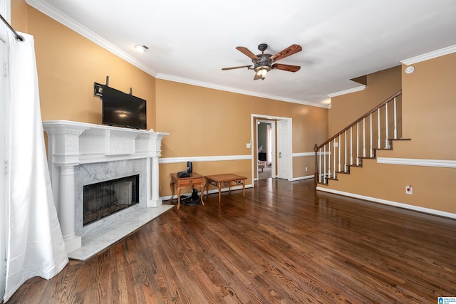 living room featuring crown molding, ceiling fan, dark wood-type flooring, and a premium fireplace