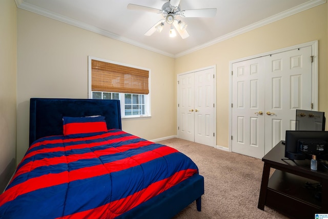 bedroom with two closets, ceiling fan, carpet floors, and crown molding