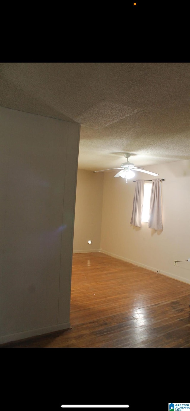 spare room featuring ceiling fan, wood-type flooring, and a textured ceiling