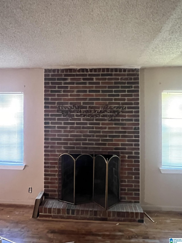 interior details with wood-type flooring, a brick fireplace, and a textured ceiling