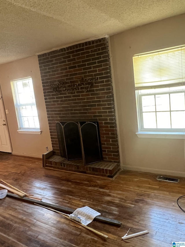 unfurnished living room featuring hardwood / wood-style flooring, a fireplace, and a textured ceiling