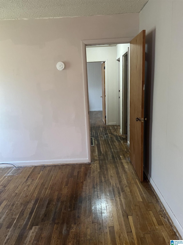 hallway with a textured ceiling and dark hardwood / wood-style floors