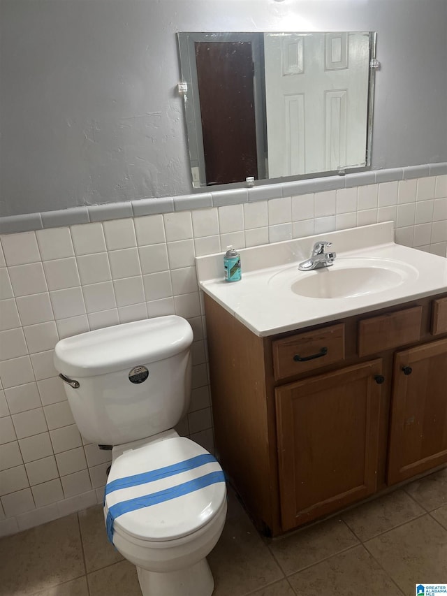 bathroom with tile patterned flooring, vanity, toilet, and tile walls