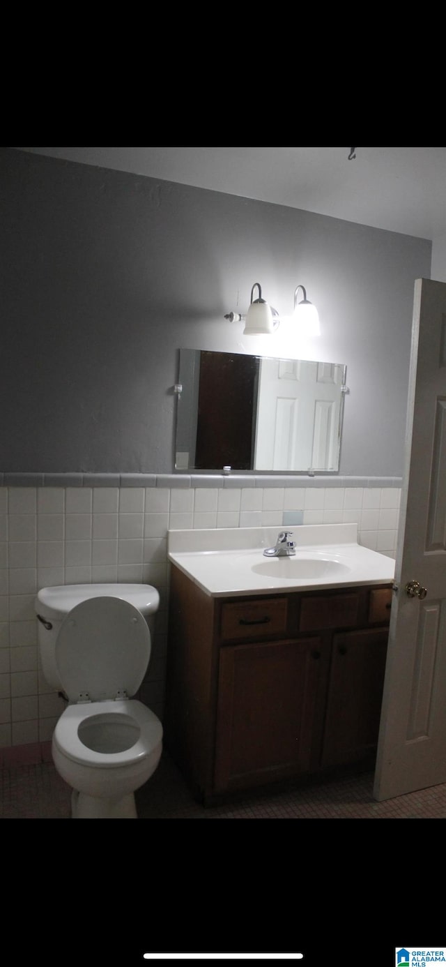 bathroom with vanity, toilet, and tile walls