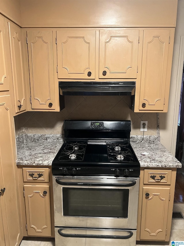 kitchen featuring backsplash, gas range, and light stone countertops