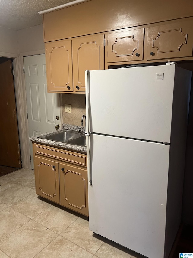 kitchen with white refrigerator, sink, and a textured ceiling