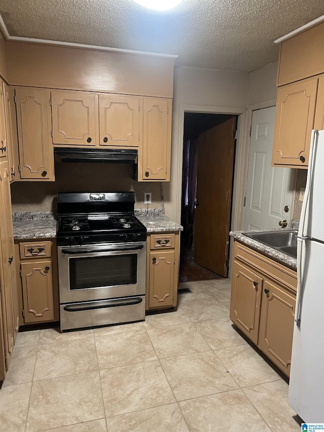 kitchen featuring sink, stainless steel range with gas cooktop, a textured ceiling, and white refrigerator