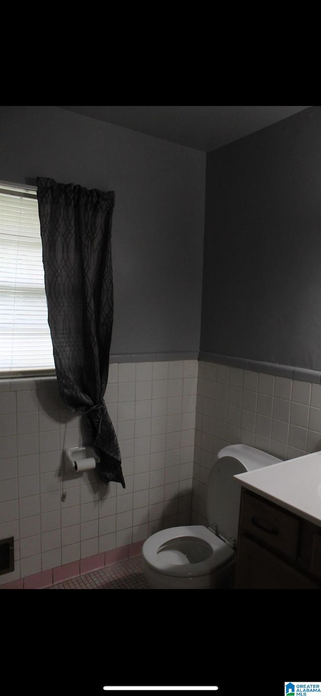 bathroom with vanity, toilet, and tile walls