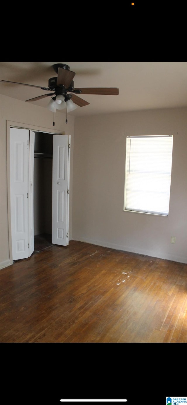 unfurnished bedroom with a closet, dark hardwood / wood-style floors, and ceiling fan