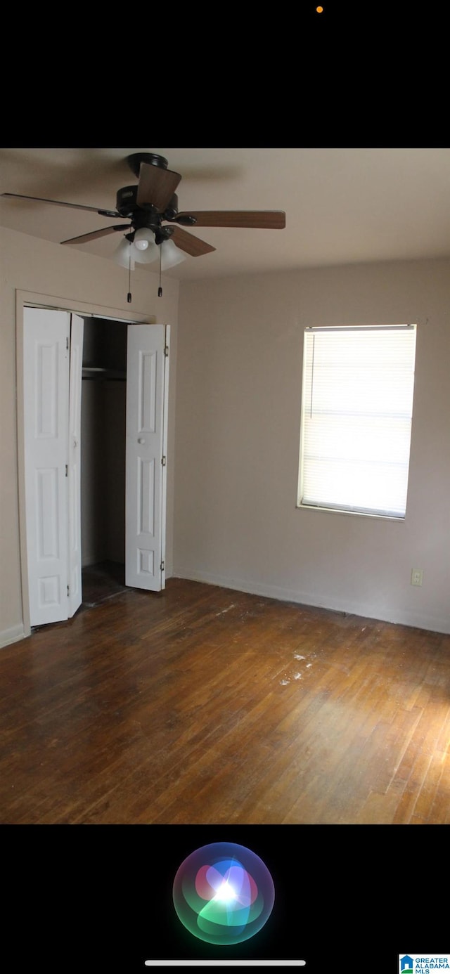 unfurnished bedroom with dark hardwood / wood-style flooring, a closet, and ceiling fan