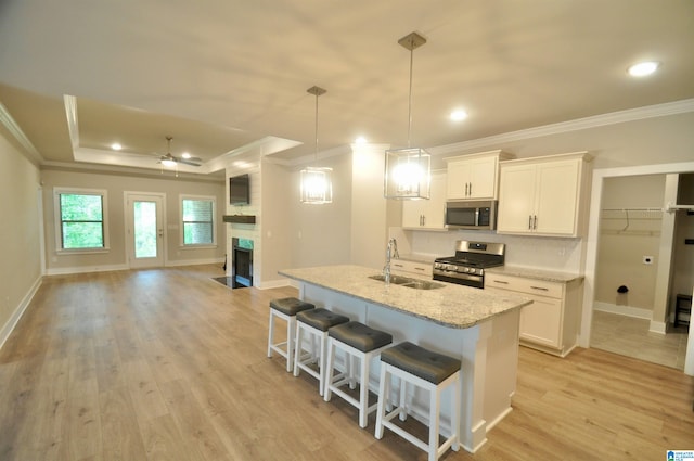 kitchen with white cabinetry, pendant lighting, stainless steel appliances, ceiling fan, and light hardwood / wood-style flooring