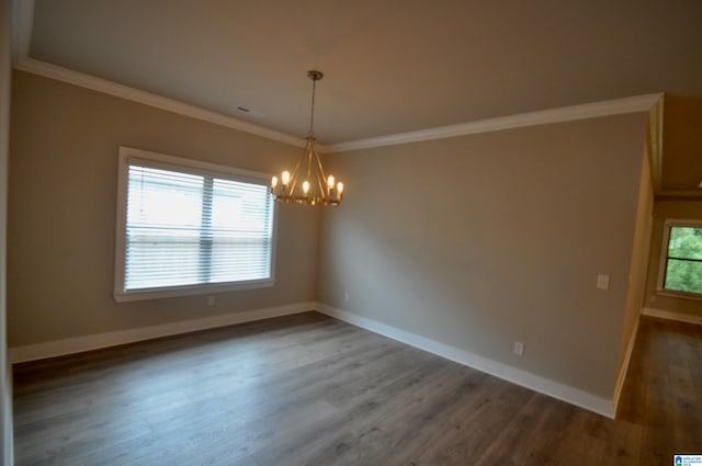 empty room with ornamental molding, dark hardwood / wood-style floors, a chandelier, and a healthy amount of sunlight