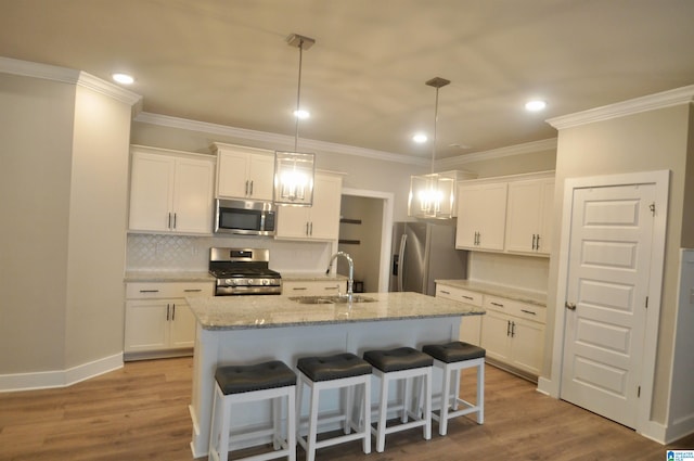 kitchen with sink, white cabinets, hanging light fixtures, a center island with sink, and appliances with stainless steel finishes