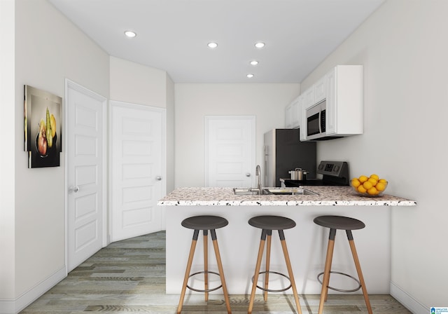 kitchen featuring white cabinets, kitchen peninsula, a kitchen bar, stainless steel appliances, and light hardwood / wood-style floors