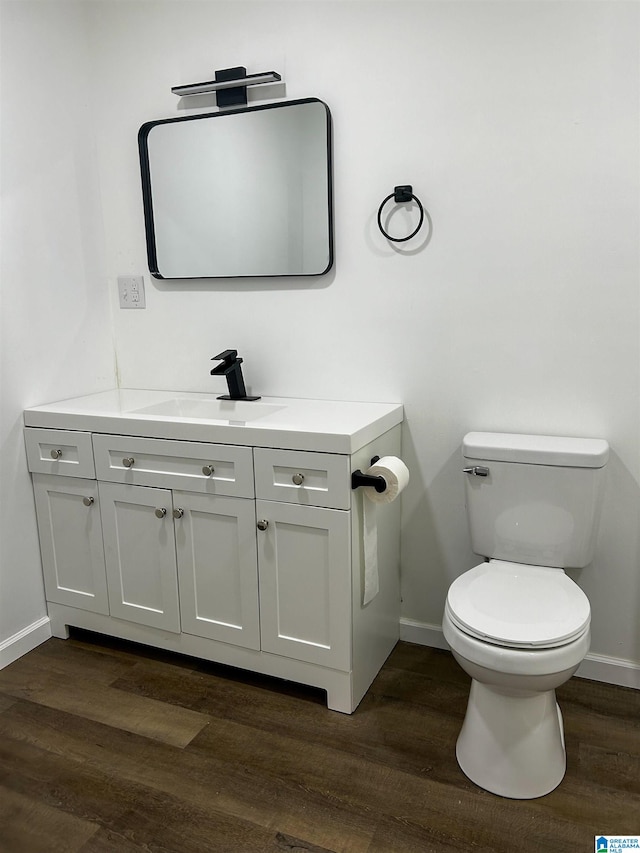 bathroom with wood-type flooring, vanity, and toilet