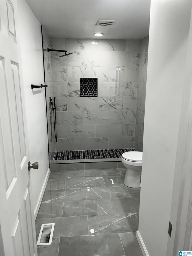 bathroom featuring a tile shower and toilet