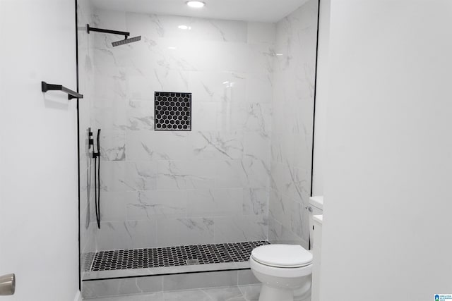 bathroom featuring a tile shower, vanity, and toilet