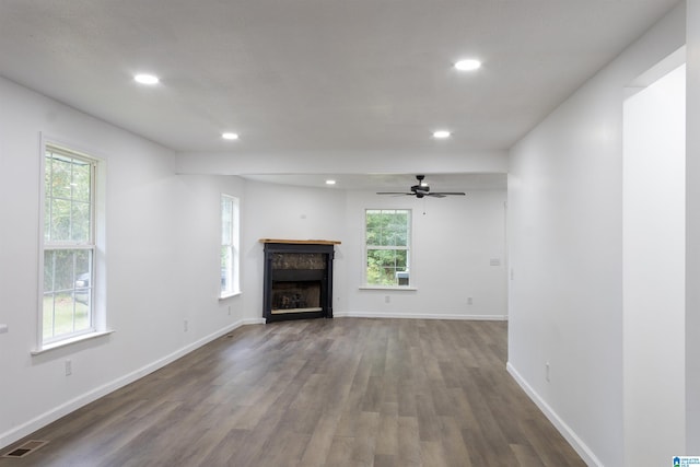 unfurnished living room with ceiling fan, dark hardwood / wood-style floors, and a wealth of natural light