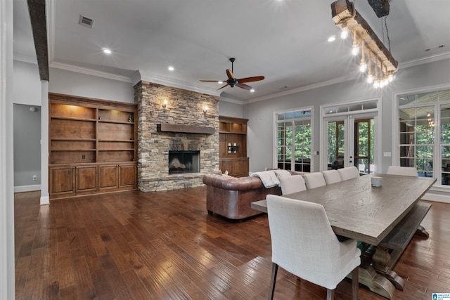 dining space with ceiling fan, a stone fireplace, dark hardwood / wood-style floors, and crown molding