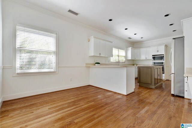 kitchen with light wood-type flooring, white cabinetry, kitchen peninsula, and stainless steel refrigerator