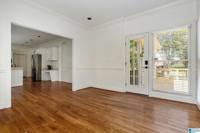 interior space featuring a healthy amount of sunlight, ornamental molding, and dark hardwood / wood-style flooring