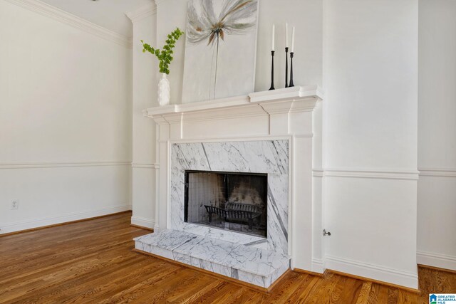 interior details featuring wood-type flooring, a high end fireplace, and crown molding