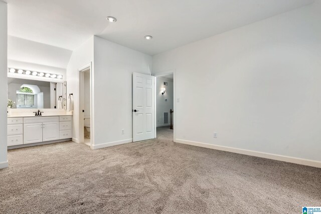 unfurnished bedroom featuring connected bathroom, carpet flooring, and sink