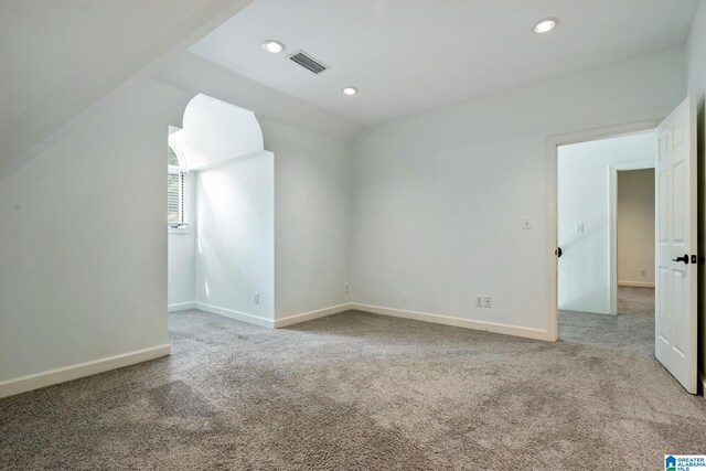 carpeted spare room featuring vaulted ceiling