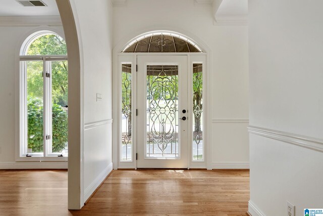 foyer entrance featuring light hardwood / wood-style floors, a healthy amount of sunlight, and crown molding