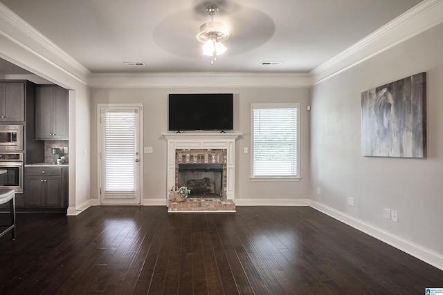 unfurnished living room with crown molding, dark hardwood / wood-style floors, ceiling fan, and a brick fireplace