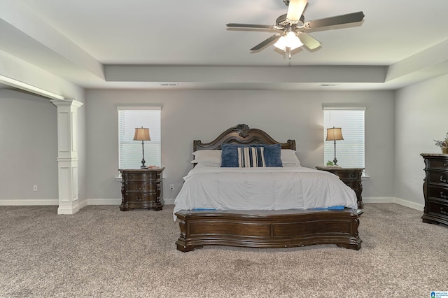 carpeted bedroom featuring ceiling fan, a raised ceiling, and ornate columns