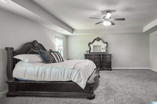 bedroom featuring a raised ceiling, carpet flooring, and ceiling fan