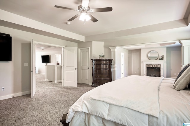 bedroom featuring a tiled fireplace, ceiling fan, and carpet floors