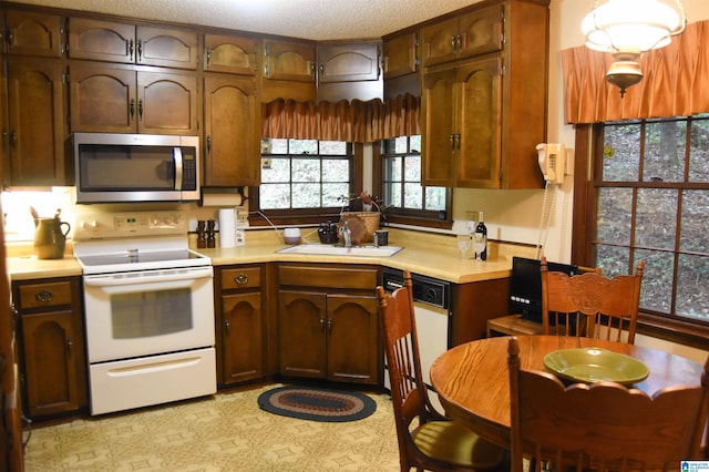 kitchen with a textured ceiling, sink, and white appliances