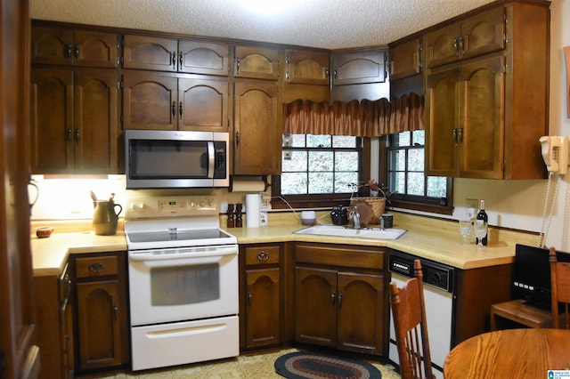 kitchen with a textured ceiling, sink, and white appliances