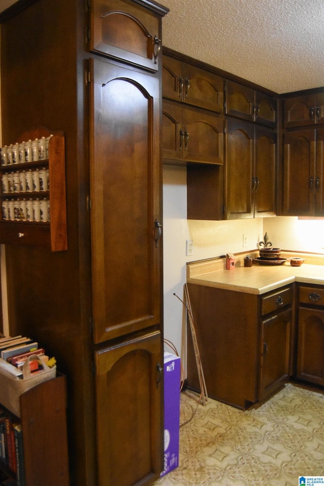 kitchen with a textured ceiling and dark brown cabinetry