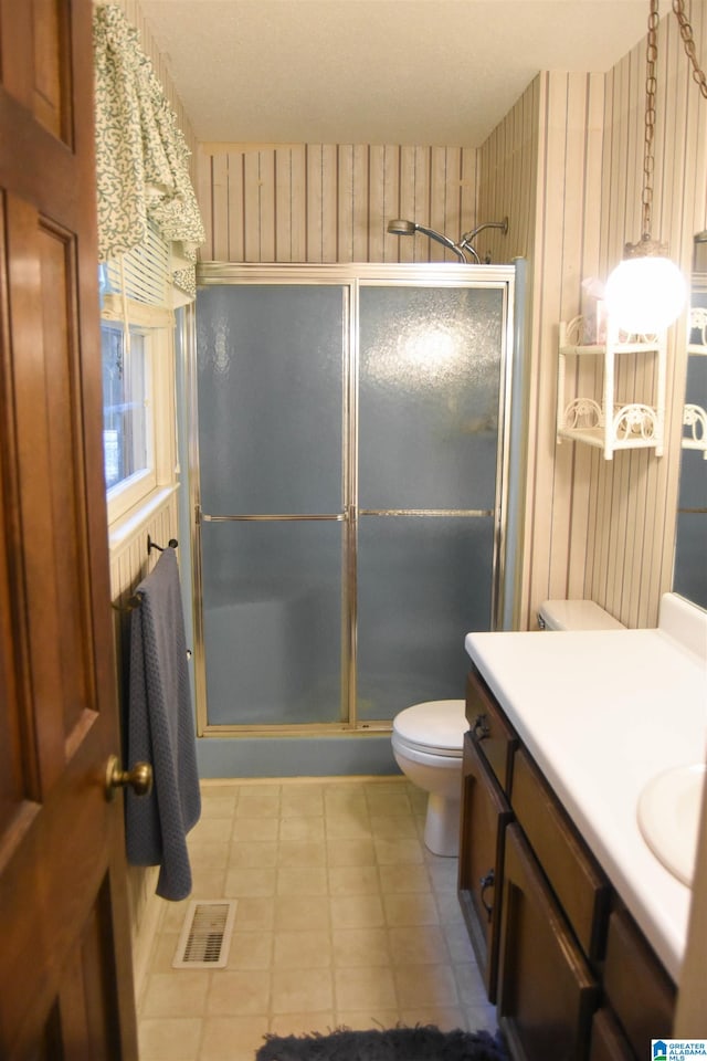 bathroom featuring vanity, toilet, and a shower with door