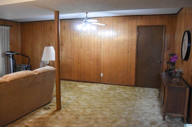 interior space featuring wooden walls, ceiling fan, light colored carpet, and a textured ceiling