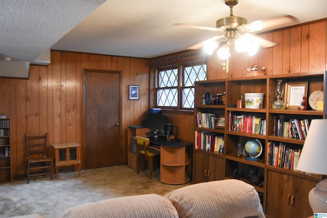 interior space with wood walls, ceiling fan, light colored carpet, and a textured ceiling