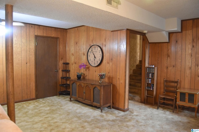 carpeted entryway with a textured ceiling and wooden walls