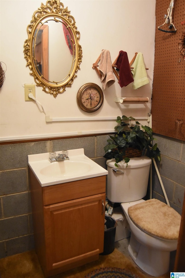 bathroom featuring vanity, tile walls, and toilet