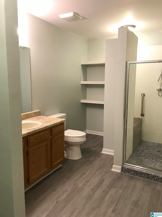 bathroom featuring vanity, hardwood / wood-style flooring, toilet, and a shower with door